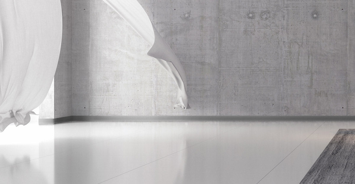 White curtain partially drawn on a gray wall with a wooden floor.