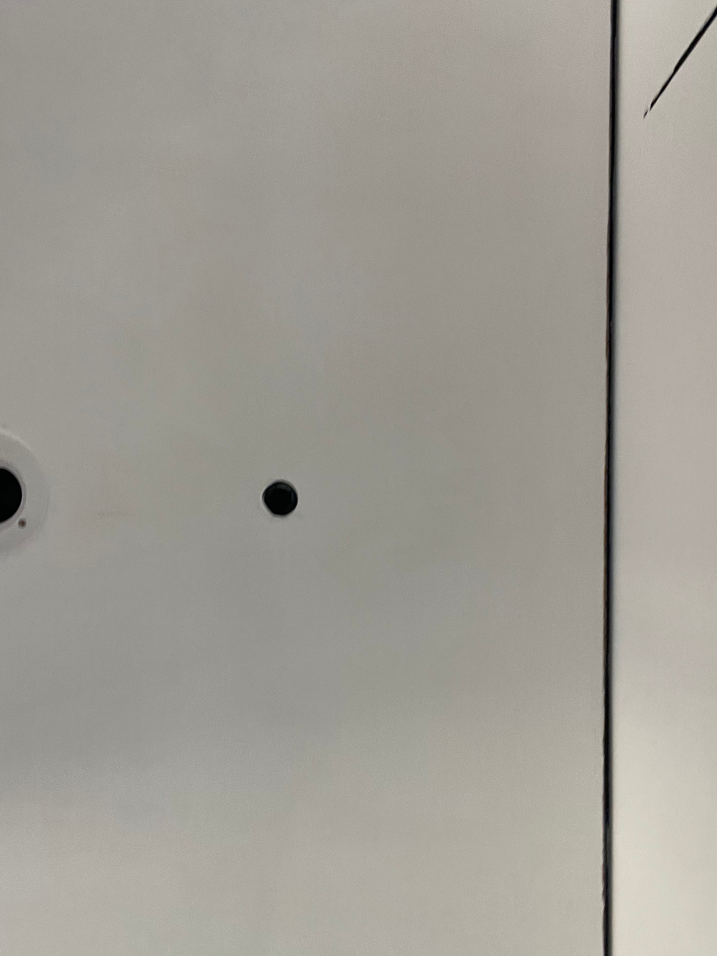 Close-up of a ceiling surface with two small black light spots and ceiling shadow gap profile.