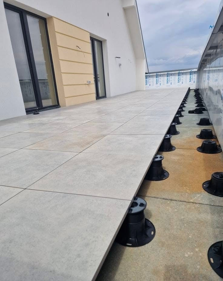 Outdoor concrete floor with black pedestals along a building wall.